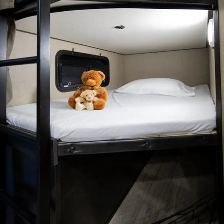Bunk bed with white bedding, a pillow, and two teddy bears, showcasing the comfort of the Thomas Payne Adjustable Microfiber by Lippert Comp.