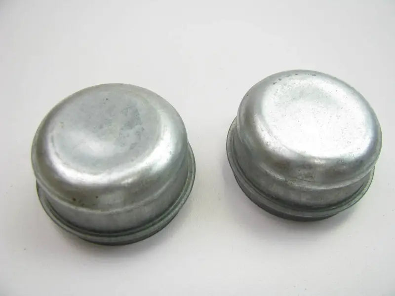 Two silver metal grease caps for Raybestos Electric Trailer Brakes on electric trailer brakes