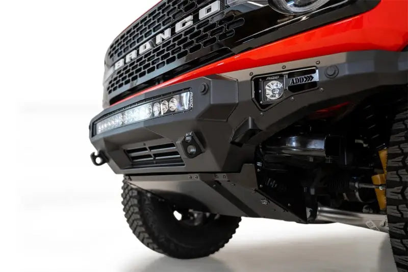 Addictive Desert Designs 2021+ Ford Bronco Stealth Fighter Front Bumper with Winch Mount in hammer black and satin black finish, featuring light bar and cube light mounts.