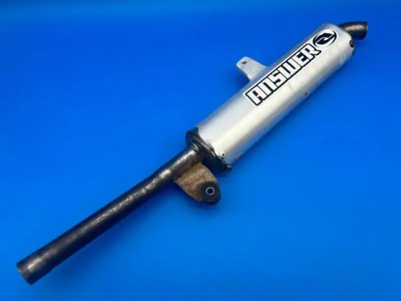 Motorcycle exhaust pipe next to Answer 23 Aerlite Glove White Black in youth XL size