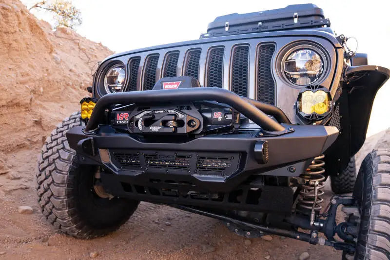 DV8 Offroad 18-23 Wrangler JL/Gladiator JT Spec Series Front Bumper installed on a Jeep, featuring a high clearance design and a mounted Warn 12s EVO winch.