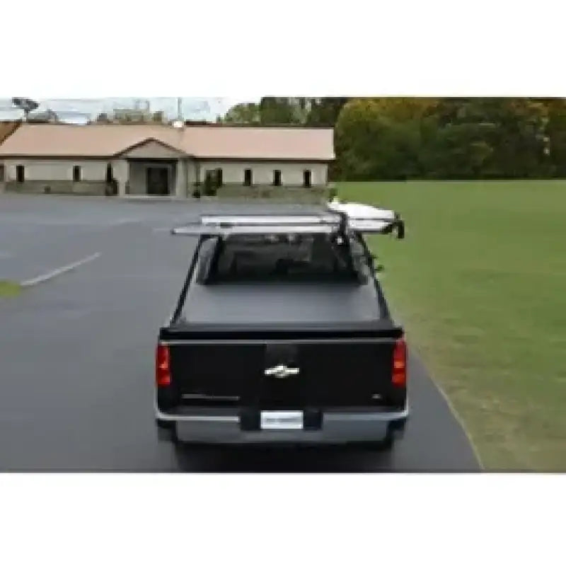 Black pickup truck with bed cover and ladder rack.