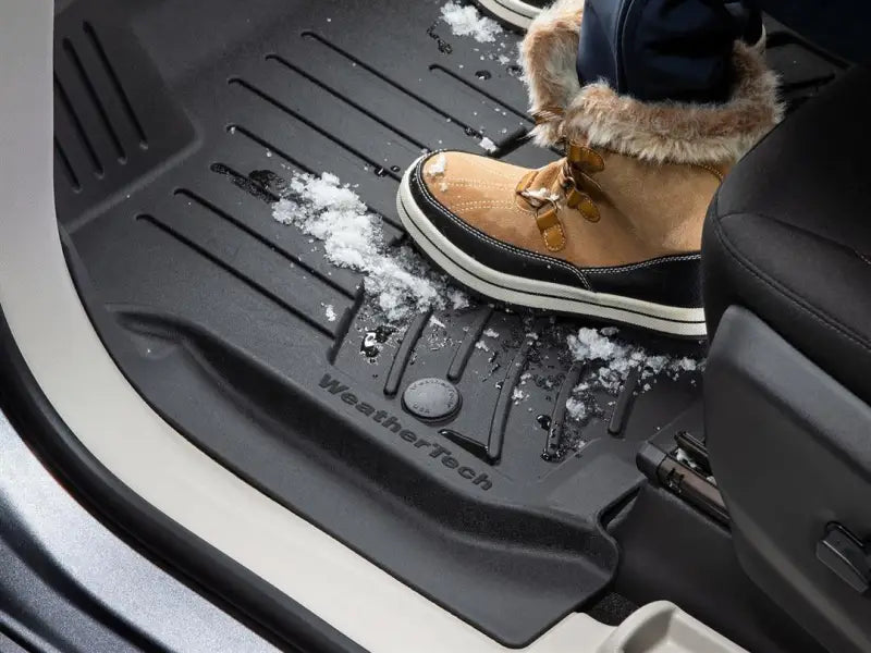 WeatherTech FloorLiner in black with channels and reservoir holding snow, showcasing molded fit and applied WeatherTech logo.