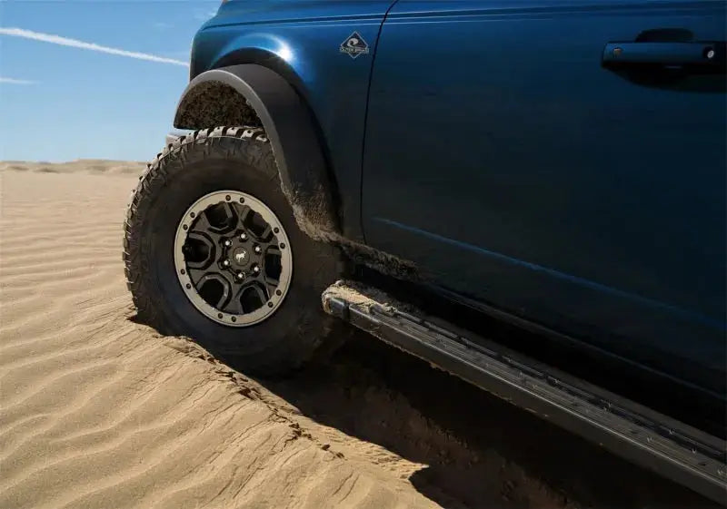 Ford Racing 21-22 Bronco Sasquatch Fender Flare Kit on a blue Bronco, enhancing style and functionality while off-roading in sandy terrain.