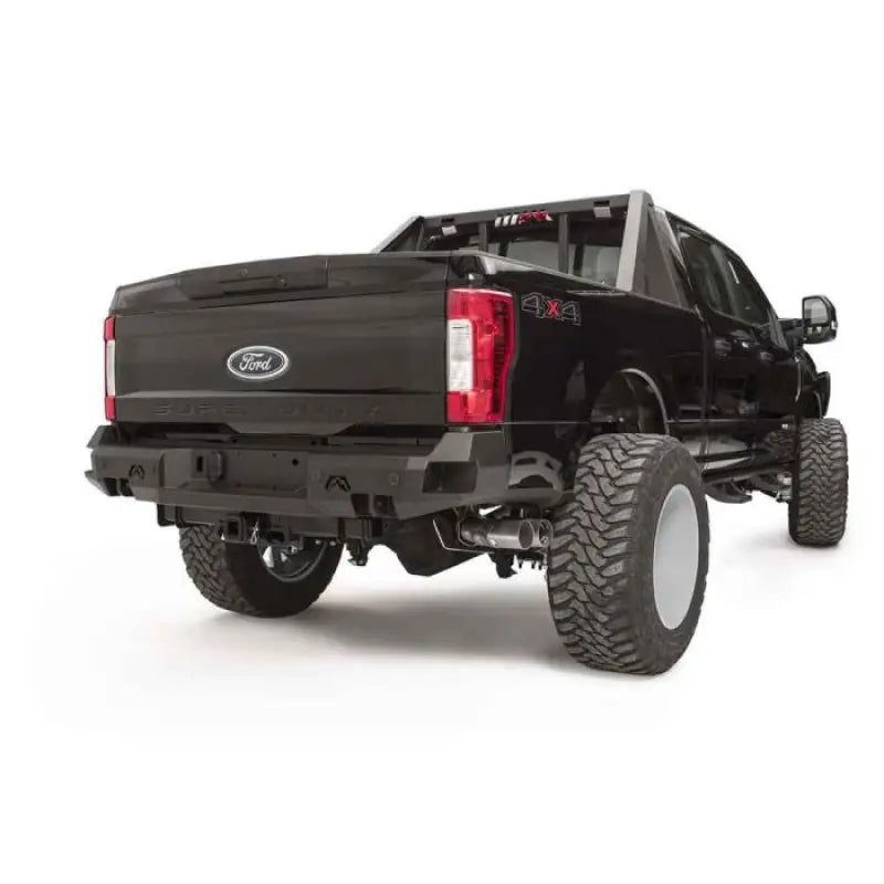 Fab Fours FS17-W4151-1 rear sensor bumper on a black Ford F250/F350 truck showcasing robust construction, integrated sensor openings, and stylish design.