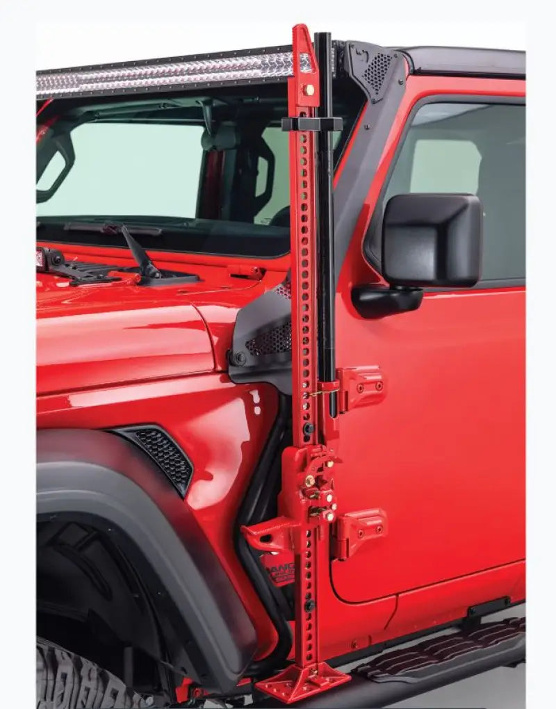 Jack Mount Hi-Lift Jack by Go Rhino mounted to driver side front quarter panel of a red Jeep Wrangler, black mild steel, powder-coated finish.