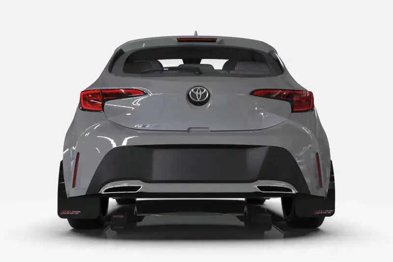 Light gray Toyota hatchback with rally armor black mud flaps and dual exhaust pipes