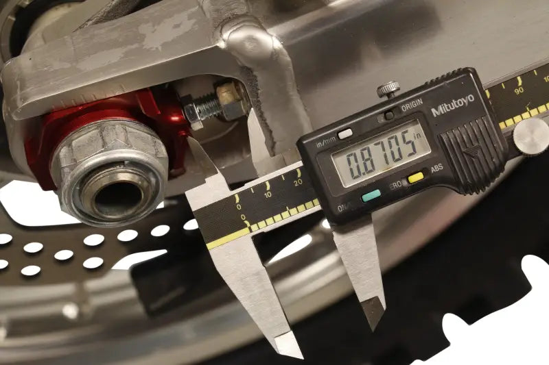 Digital caliper measuring motorcycle part with 17-205 Axle Blocks Elite Hon Red