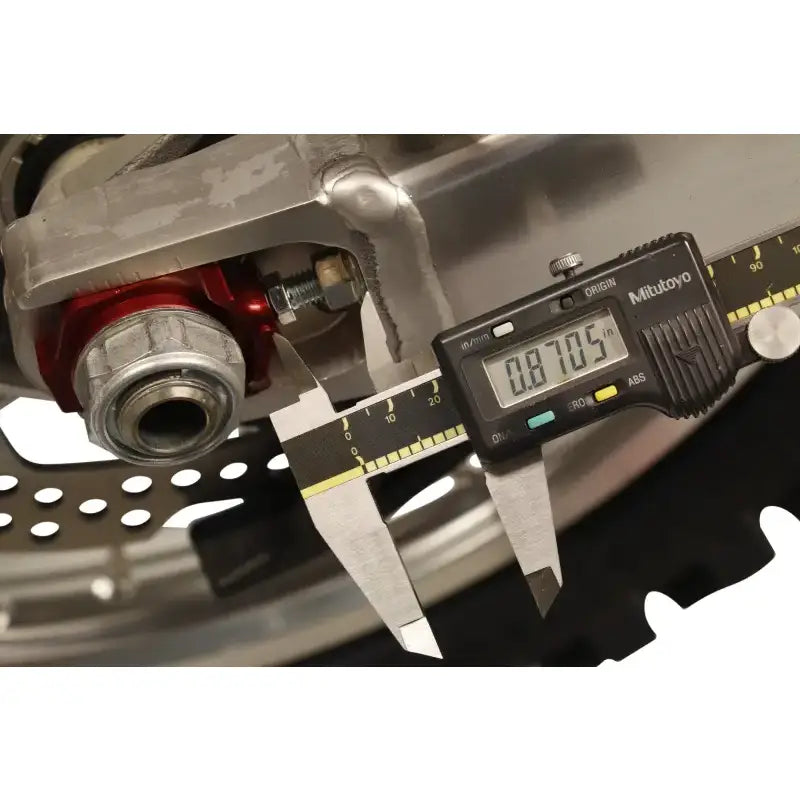 Digital caliper measuring motorcycle part with 17-205 Axle Blocks Elite Hon Red