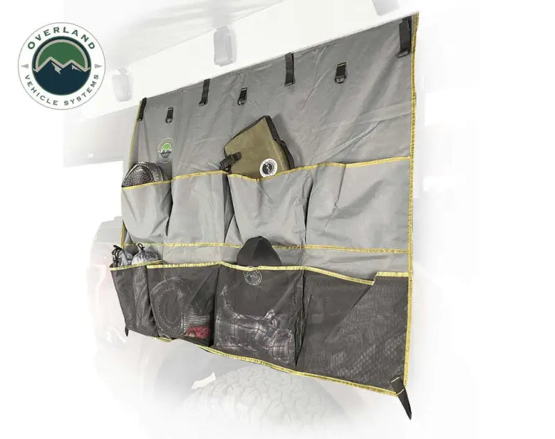 Overland Vehicle Systems 18089911 Vcl Roof Top Tent and Awning Camp Organizer hanging on a vehicle, showcasing its durable pockets for convenient storage and organization.