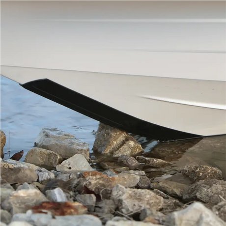 White 10' Keel Protector from KeelGuard safeguarding a boat's bow from abrasion and impact on rocky shore.