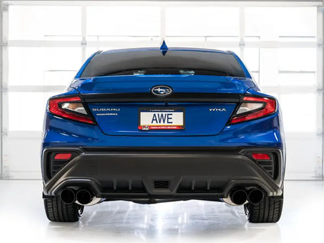 Blue Subaru WRX with AWE Track Exhaust displayed in a garage, showcasing dual exhaust pipes and AWE branding on the license plate.