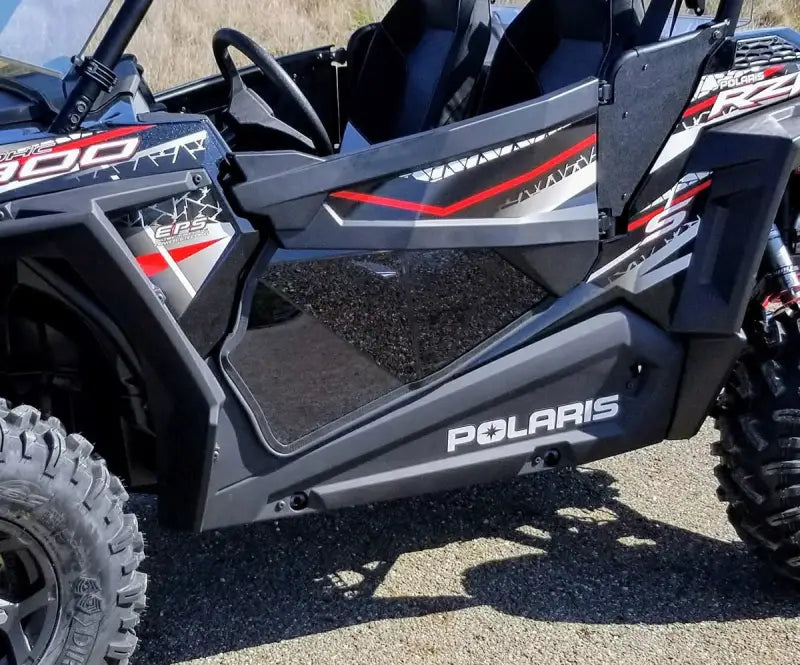Black Polaris RZR with spike lower door and aggressive tires for off-road fun