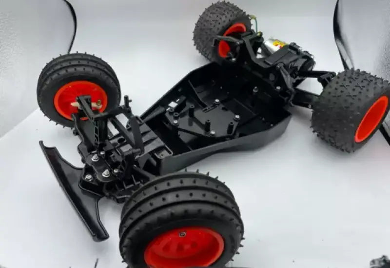 Black RC car chassis with red-rimmed tires for 579006 Speedfx -6An Blu Fuel Cell Bulkhead