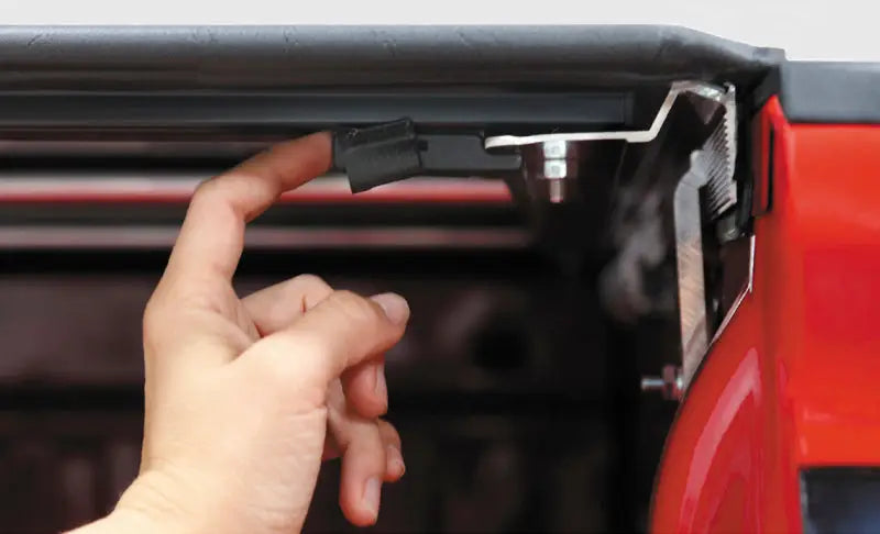 Close-up view of a hand securing the Access Tonnosport Roll-Up Cover on a 2022 Hyundai Santa Cruz with a 4ft bed.