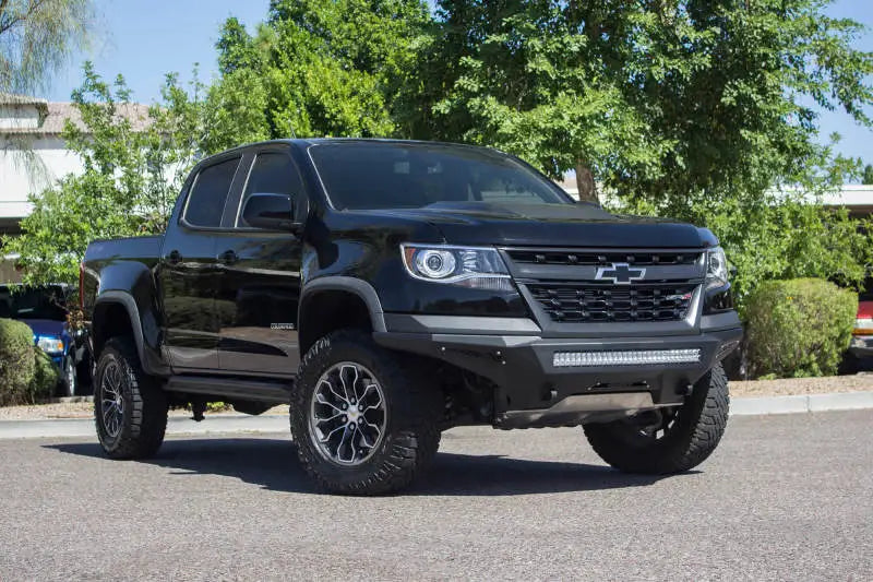 2019 Chevy Colorado ZR2 with black paint, lifted suspension, large off-road tires, and Addictive Desert Designs Stealth Fighter bumper