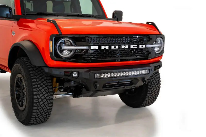 2021 Ford Bronco featuring the Addictive Desert Designs Stealth Fighter Front Bumper with Winch Mount, showcasing high clearance, hammer black powder coat finish, and integrated light bar.