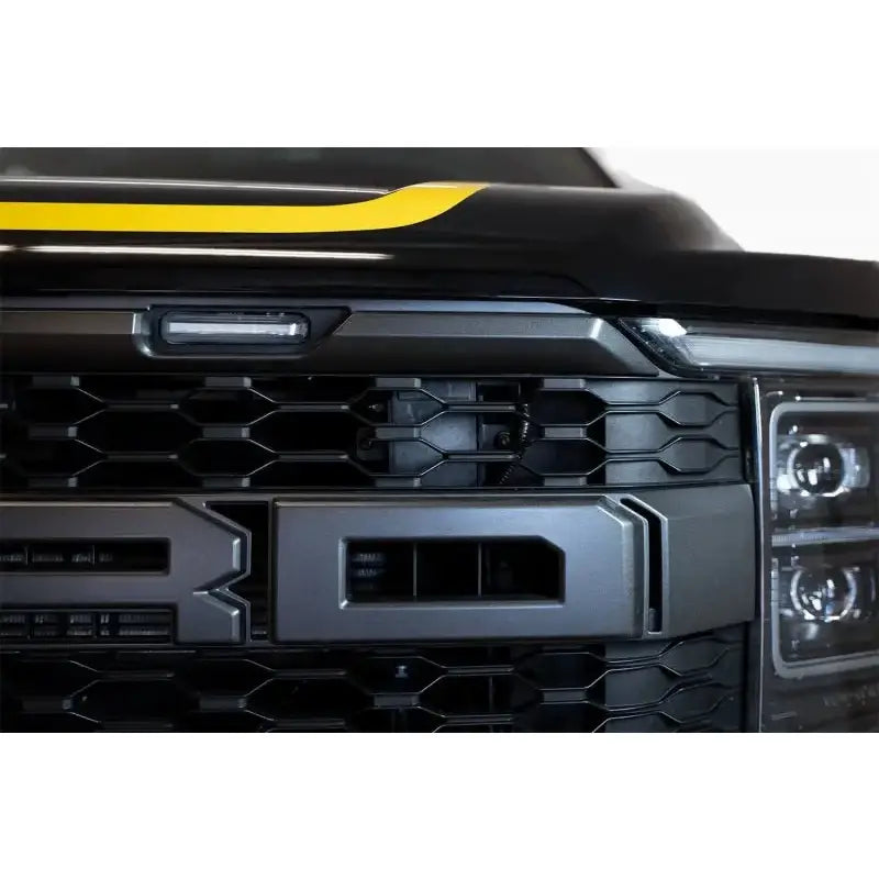 Addictive Desert Designs 21-22 Ford Raptor Adaptive Cruise Control Relocation Bracket, Hammer Black, installed on the front grille of the truck, makes room for ADD Offroad Bronco Front Bumper.