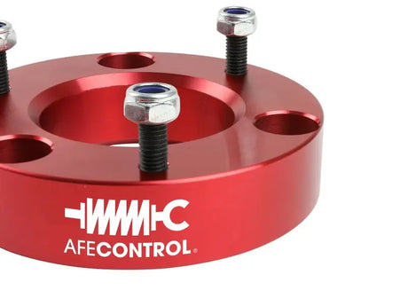 Red metal spacer with bolts for aFe Control leveling kit on Ford F-150 trucks
