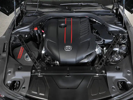 Car engine with red stripes showing aFe CONTROL suspension strut brace for Toyota GR Supra