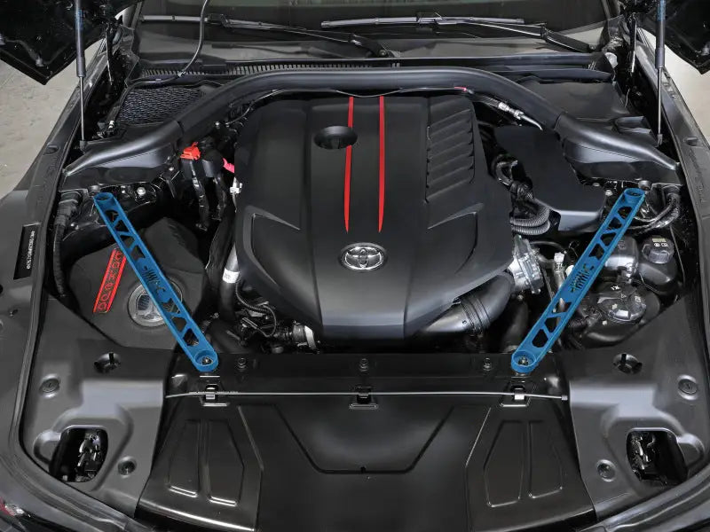 Engine bay of a Toyota GR Supra with aFe Control suspension strut brace and blue accents
