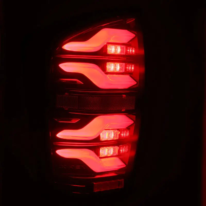 AlphaRex 16-21 Toyota Tacoma LUXX LED Taillights shown with vibrant red illumination, highlighting sleek black and red design, ideal for RV, Automotive, Powersports, off-road, marine, exterior, and truck accessories. Enhances safety with Activ Light and Sequential Signal features. Lights, AVADA - Best Sellers