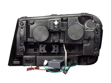 Rear view of black Chevrolet Trailblazer projector headlight set with wiring and connectors