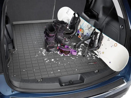 Car trunk with winter sports gear showing the durable cargo area liner in black