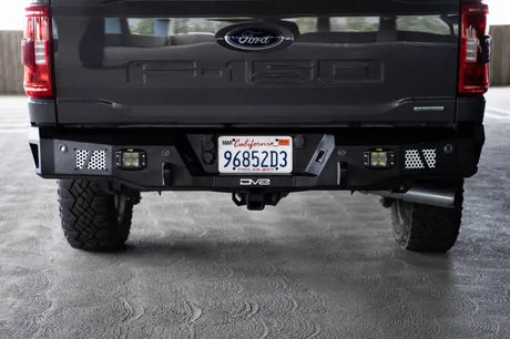 DV8 Offroad MTO Series Rear Bumper on a 2021-2023 Ford F-150, featuring flush mount light pods, utility steps, and aluminum accent panels.