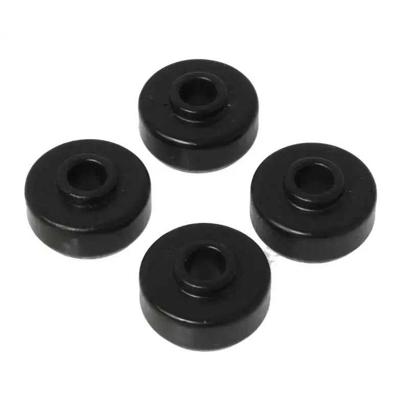 Four black rubber bushings from the Energy Suspension Universal Black Shock Bushing Set are arranged in a circular pattern against a white background. Manufactured by Energy Suspension, these cylindrical polyurethane bushings with central holes are commonly used in automotive and industrial applications for stability and noise reduction.