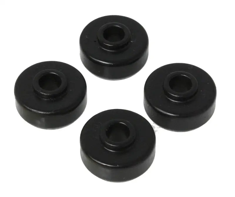 Four black rubber bushings from the Energy Suspension Universal Black Shock Bushing Set are arranged in a circular pattern against a white background. Manufactured by Energy Suspension, these cylindrical polyurethane bushings with central holes are commonly used in automotive and industrial applications for stability and noise reduction.