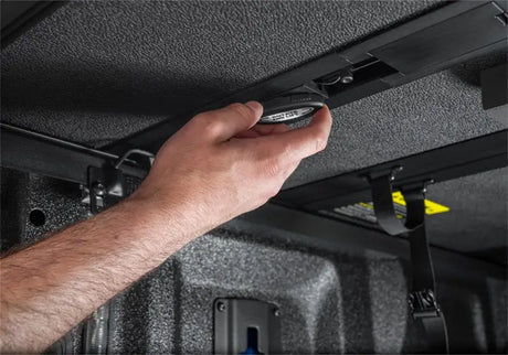 Hand adjusting a black circular knob on Extang Solid Fold ALX for Dodge Ram Bed