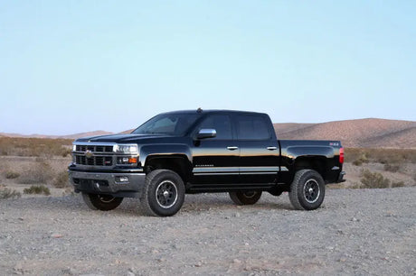Black pickup truck with large off-road tires, fitted with Fabtech 4in budget UCA system