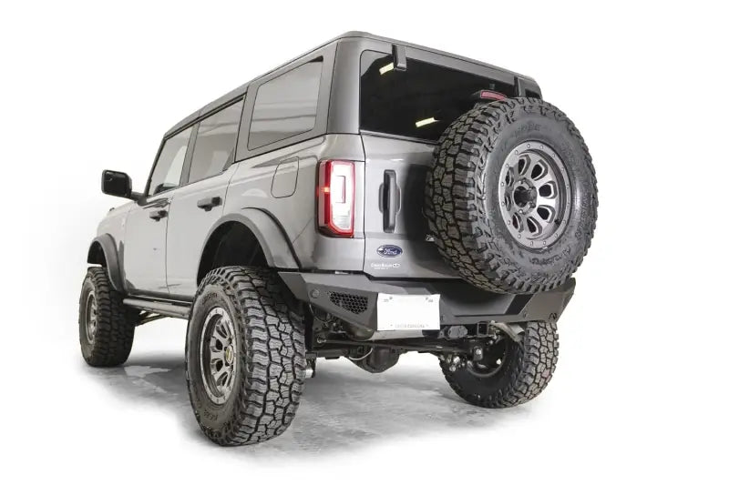 Rear view of an off-road vehicle featuring the FB21-Y5251T-1 Fab Fours Tire Carrier Bracket securely holding a rugged spare tire for adventurous journeys.