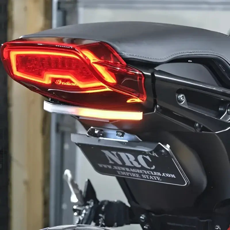 Rear of an Indian FTR 1200 motorcycle with custom-designed fender eliminator featuring a 2-position side mount license plate bracket, highlighting sleek red taillights, surrounded by high-quality RV, automotive, powersports, and off-road accessories.