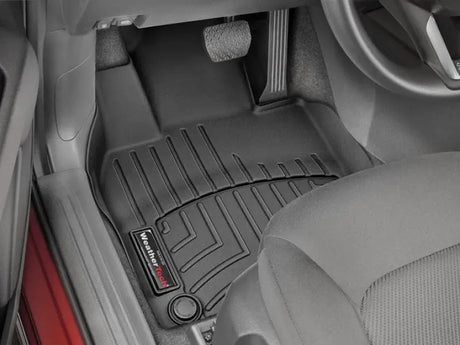WeatherTech black molded floor liner with channels and reservoir to direct and hold fluids for car interior protection.