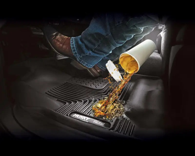 Husky Liners ® X-act Contour ® floor liner with molded fit, raised channels, and edges, shown protecting a car floor from spilled liquid, black, TPE material, 2-piece set.