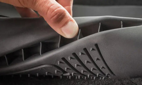 Close-up of hand flexing black Husky Liners® X-act Contour® floor liner with raised ridge and stay-put cleats.