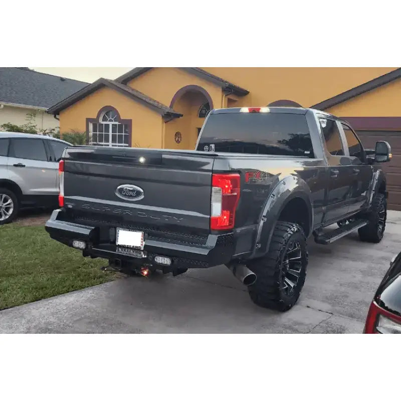 FS17-T4150-1 Fab Fours rear bumper installed on Ford F250 Super Duty in a driveway, showcasing robust construction and sleek design.
