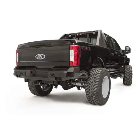 "FS17-W4151-1 Fab Fours 17 F250-F350 Rear Sensor Bumper installed on a black Ford Super Duty truck, showcasing robust construction, integrated sensor openings, and enhanced style for superior protection and functionality."