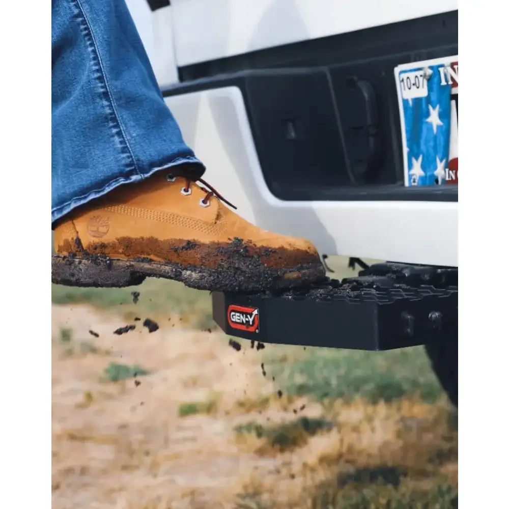 Mud-covered boot stepping on GH-030 Gen-Y Hitch with 2' shank, heavy-duty design, and serrated surface for secure towing connection.