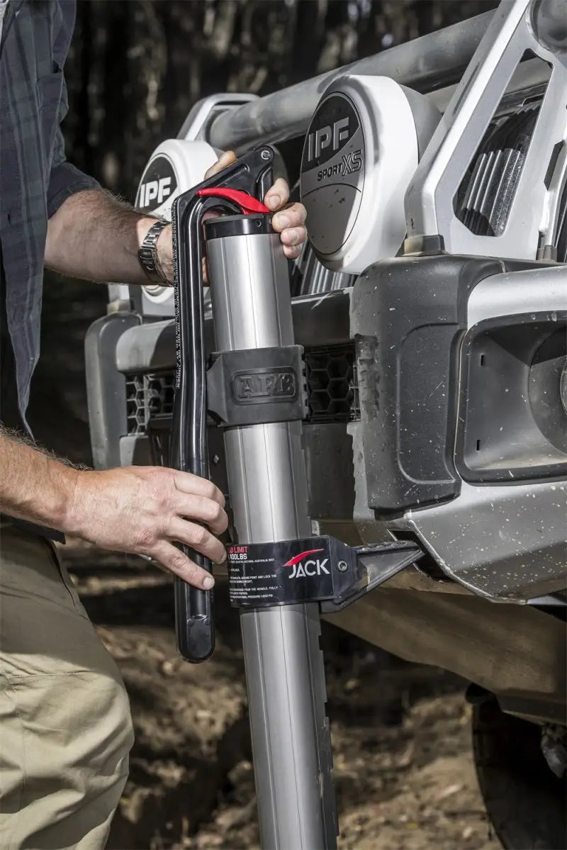 Person using ARB hydraulic jack to lift a vehicle off-road.