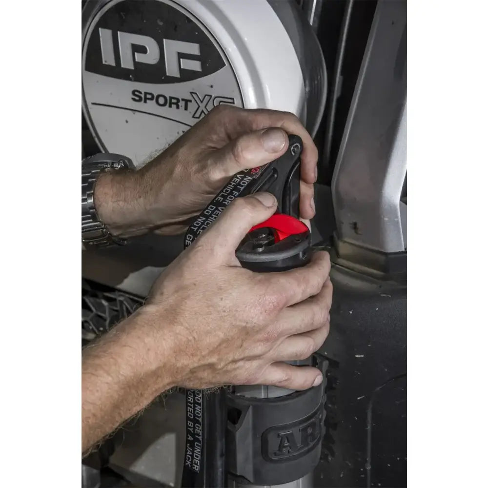 Hands operating the ARB hydraulic recovery jack with IPF lighting in the background.