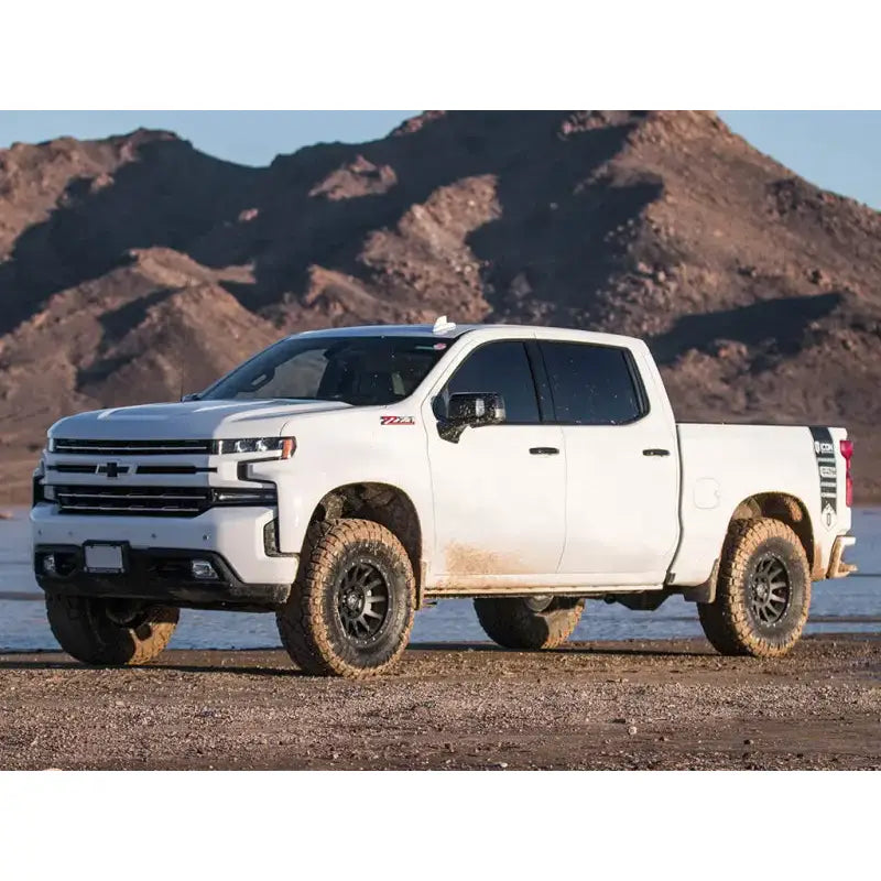White GM 1500 truck with ICON's Stage 2 Suspension System and Tubular Upper Control Arms in a mountainous terrain.