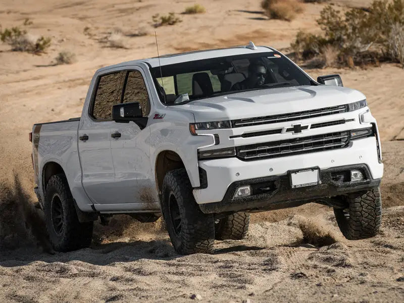 Chevrolet Silverado GM 1500 truck equipped with the ICON 2019+ 1.5-3.5in Stage 4 Suspension System with Tubular UCA driving off-road in the desert.