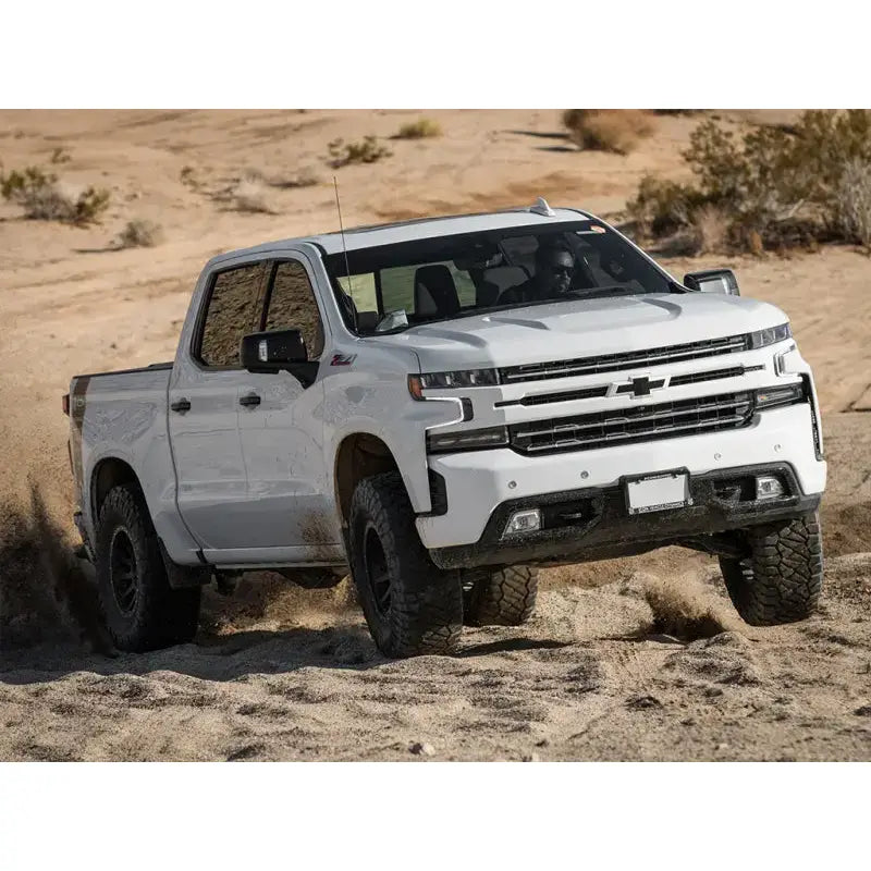 Chevrolet Silverado GM 1500 truck equipped with the ICON 2019+ 1.5-3.5in Stage 4 Suspension System with Tubular UCA driving off-road in the desert.
