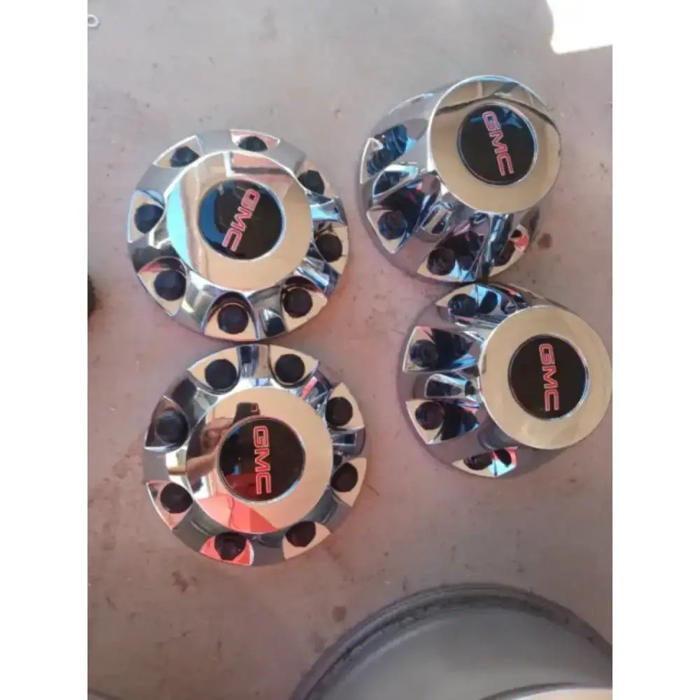 Polished chrome center caps with GMC logo, designed for Ford vehicles, enhancing wheel aesthetics.