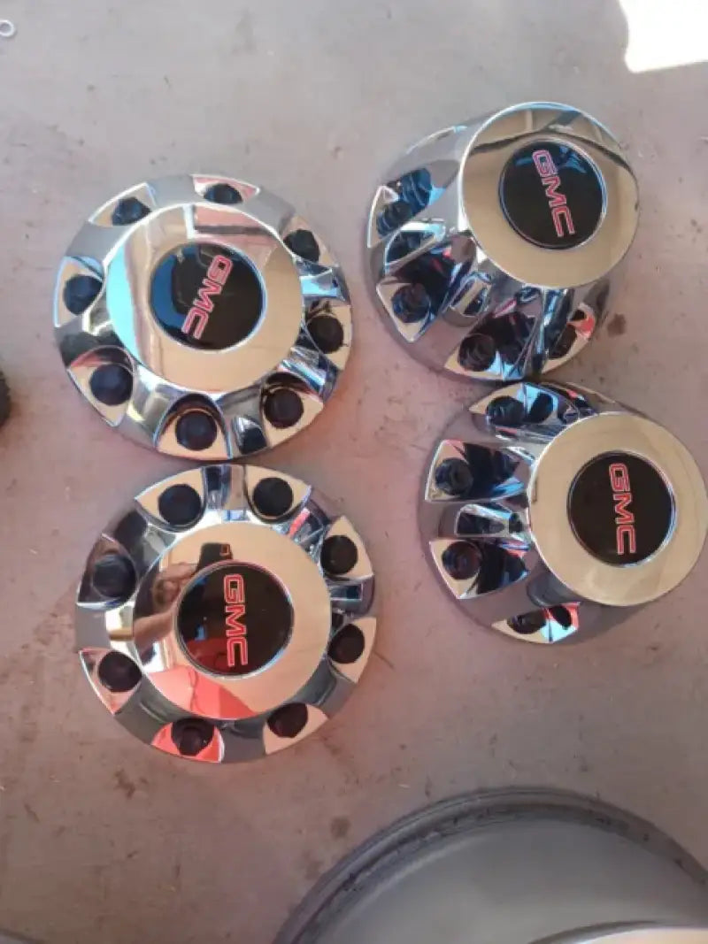 Polished chrome center caps with GMC logo, designed for Ford vehicles, enhancing wheel aesthetics.