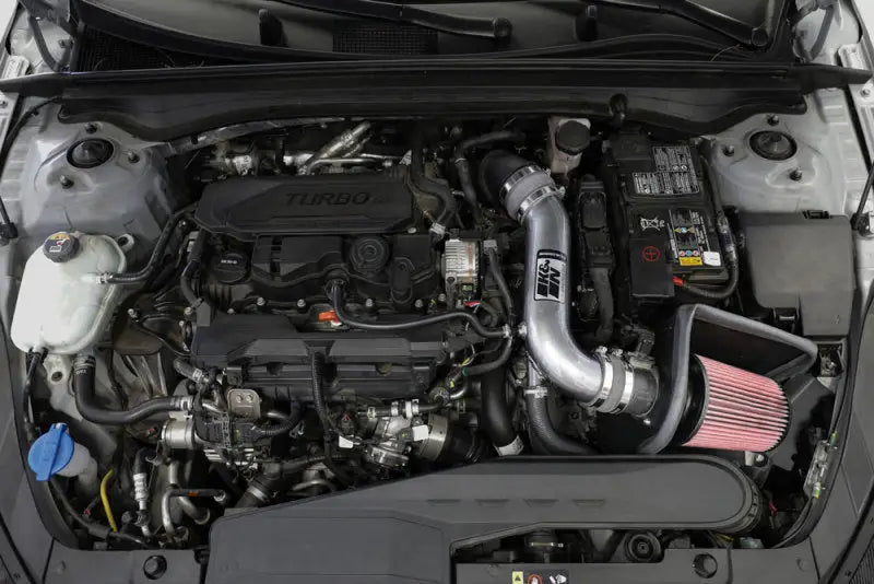 K&N 21-22 Kia K5 L4-1.6L Typhoon Air Intake installed in engine bay, featuring a mandrel-bent aluminum intake tube and oversized conical High-Flow Air Filter. Ideal for RV, automotive, powersports, off-road, marine, exterior, truck accessories, interior, truck bed, RV parts, apparel, helmets, racing, riding, BMX.
