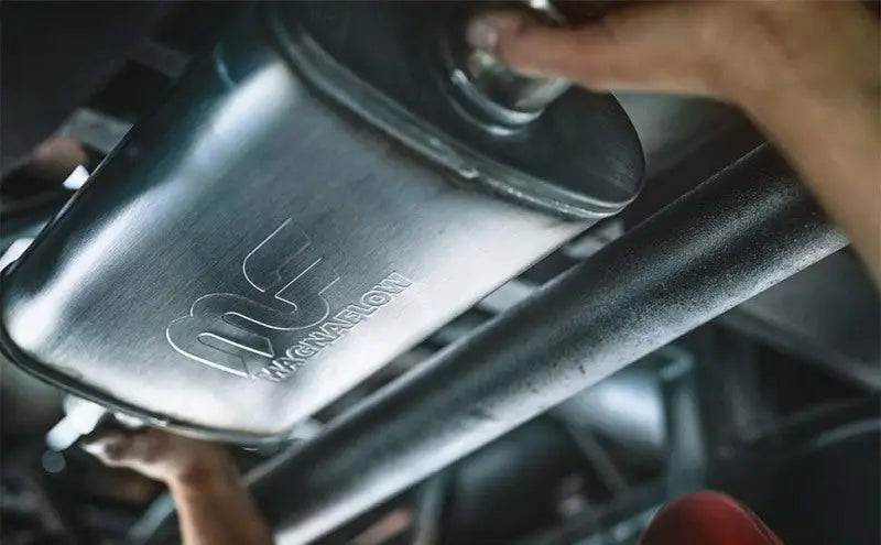MagnaFlow Muffler Mag SS 14X4X9 2.5 D/D installed on a vehicle, showcasing its durable stainless steel body with satin finish and etched MagnaFlow logo.